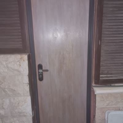 דלת עץ עם ידית מתכת במסגרת כהה