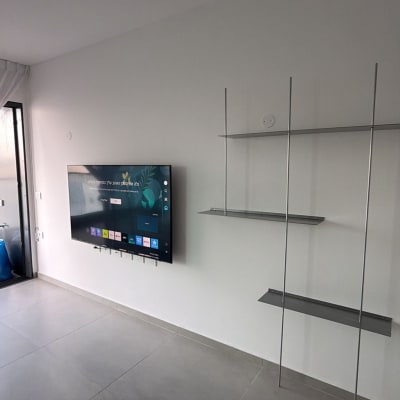 טלוויזיה מותקנת על קיר עם מדפים מתכתיים