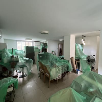 חדר עם רהיטים מכוסים בניילון ירוק לקראת צביעה