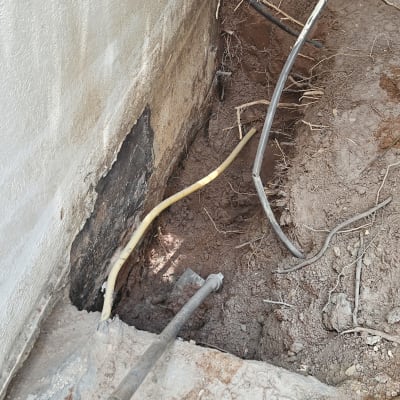 חפירה ליד קיר עם צינורות חשופים