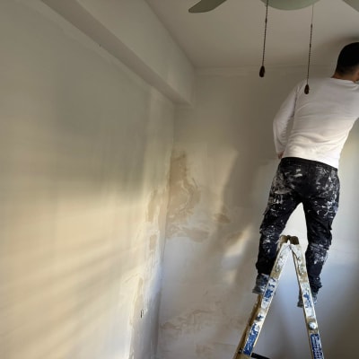 אדם צובע קיר בעזרת סולם בחדר