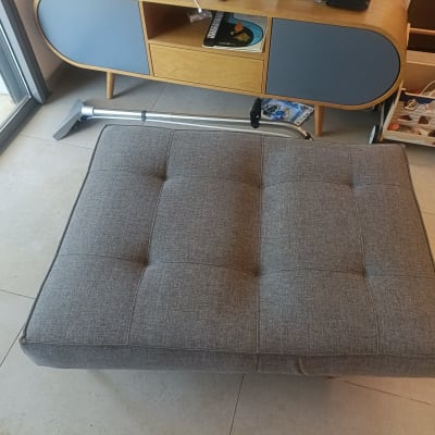 שואב אבק ליד ספה אפורה על רצפת אריחים