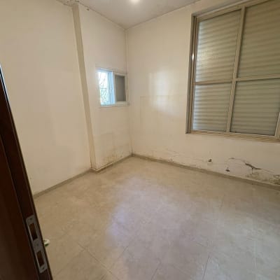 חדר ריק עם קירות מתקלפים ורצפה מרוצפת