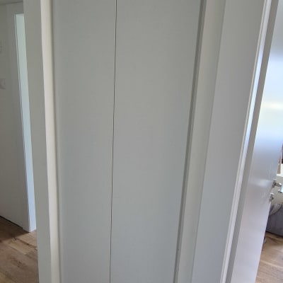 ארון לבן עם דלתות סגורות על רצפת עץ