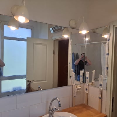 מראה חדשה מותקנת בחדר אמבטיה עם תאורה