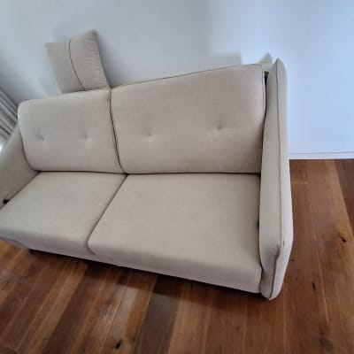 ספה בהירה על רצפת עץ ליד חלון