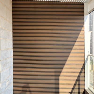 קיר עץ עם פסים אופקיים במרפסת מוארת בשמש