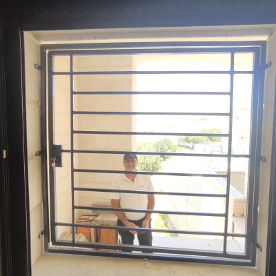 אדם עומד מאחורי סורג חלון מתכת