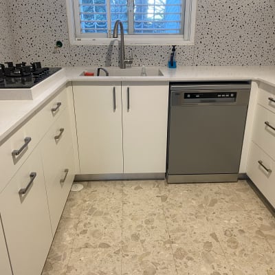 מטבח משופץ עם ארונות לבנים ומשטח עבודה חדש