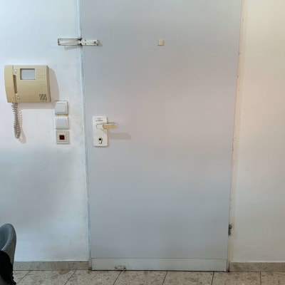 דלת מתכת עם ידית לבנה ומנעול