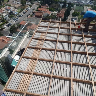 עובד מתקין דק עץ על גג בניין