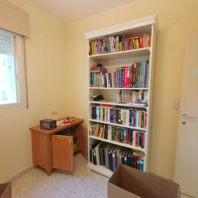 ארון ספרים עם ספרים, קופסאות קרטון פתוחות על הרצפה