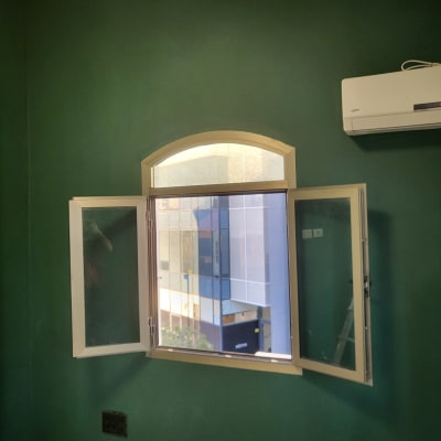 קיר צבוע בירוק עם חלון פתוח ומזגן