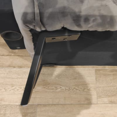 תמונת תקריב של רגל מתכת מחוברת לרהיט על רצפת עץ