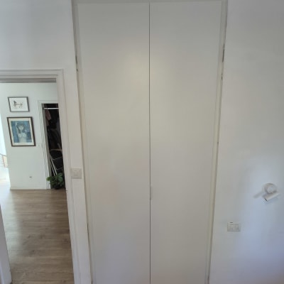 ארון לבן עם דלתות סגורות על רקע קיר לבן