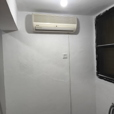 מזגן מותקן על קיר לבן עם חוט חשמל