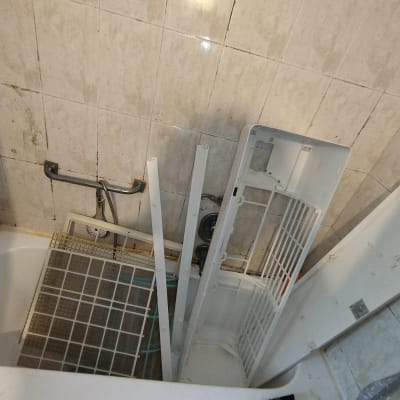 חלקי מזגן מפורקים באמבטיה עם קיר אריחים