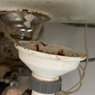 צנרת מתחת לכיור עם סימני חלודה ולכלוך