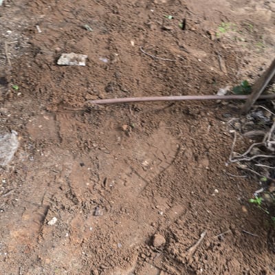 אדמה עם צינור וכלי עבודה בגינה