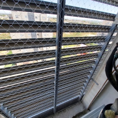 רשת מתכת מותקנת על חלון למניעת כניסת יונים