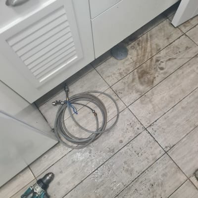 כלי עבודה וצינור על רצפה מלוכלכת ליד ארון מטבח