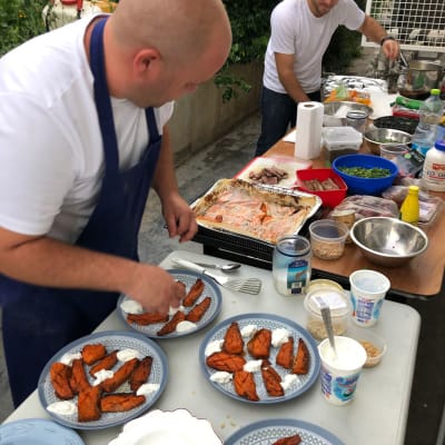 שני אנשים מכינים מנות עם ירקות ורטבים על שולחן חיצוני