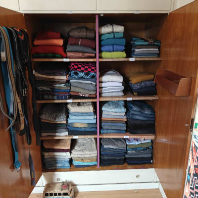 ארון בגדים מסודר עם מדפים מלאים בבגדים מקופלים