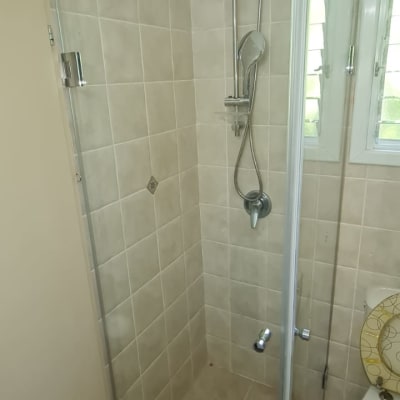 מקלחון זכוכית עם ראש מקלחת מתכת על קיר אריחים