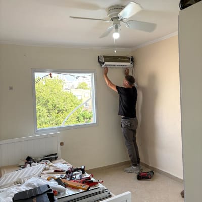 אדם מתקין מזגן בחדר עם מאוורר תקרה