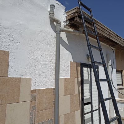 סולם נשען על קיר עם צינור ומרזב