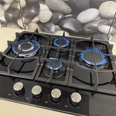 כיריים גז עם להבות כחולות על רקע אבנים דקורטיביות