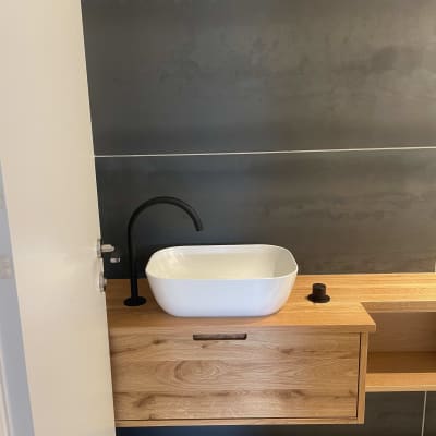 כיור לבן עם ברז שחור על ארון עץ