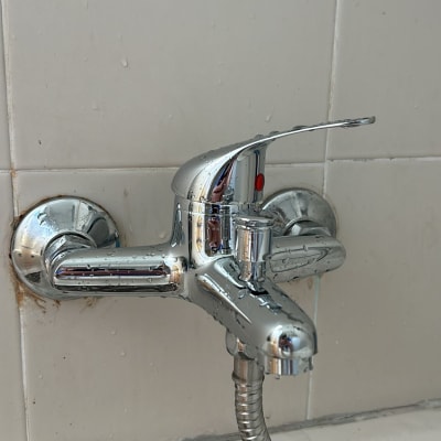 ברז כרום עם צינור גמיש על קיר אריחים