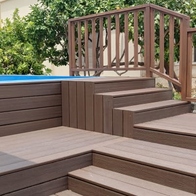 דק עץ עם מדרגות ומעקה ליד בריכה