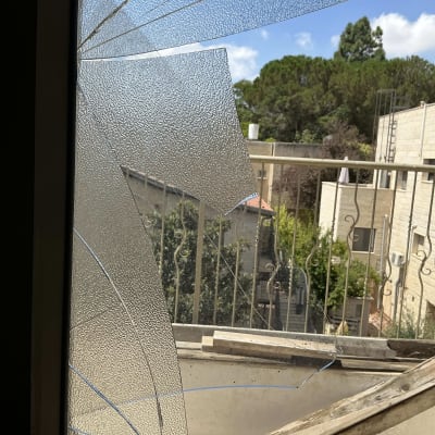 זכוכית שבורה במרפסת עם נוף לעצים ובניינים