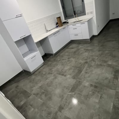 מטבח נקי עם ארונות לבנים ורצפת אריחים אפורה