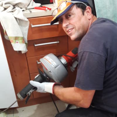 אדם מחזיק מכשיר אינסטלציה ליד ארון מטבח