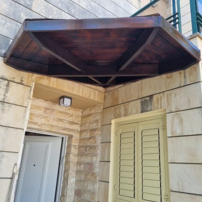 סככת עץ מעל דלת כניסה לבית