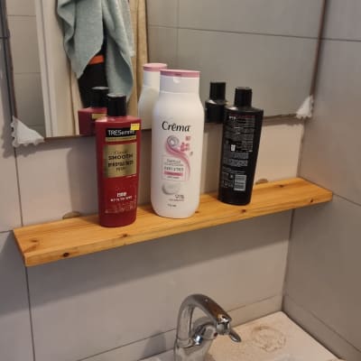 מדף עץ עם מוצרי טיפוח מעל כיור בחדר אמבטיה