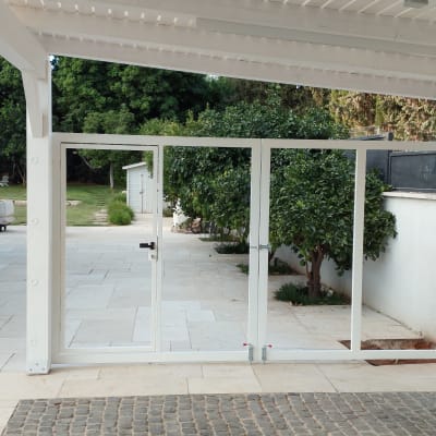 מסגרת דלת זכוכית לבנה בחצר עם עצים וריצוף אבן