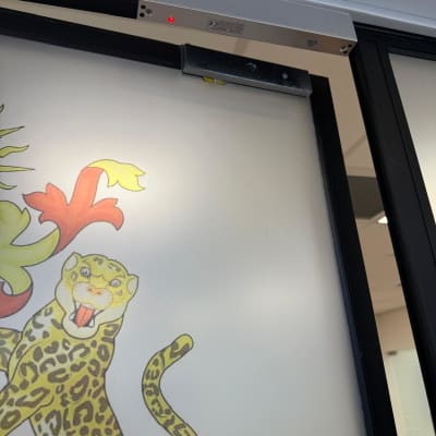 מכשיר אינטרקום מותקן על דלת זכוכית עם עיטור נמר