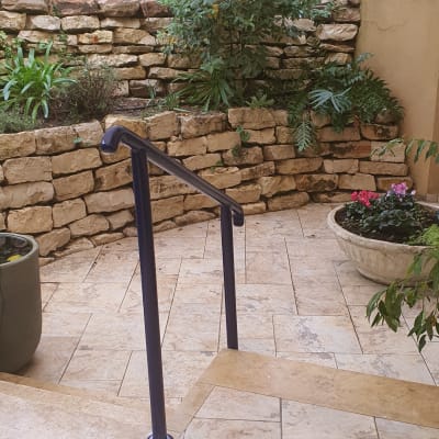 מעקה מתכת כחול על רצפת אבן בגינה