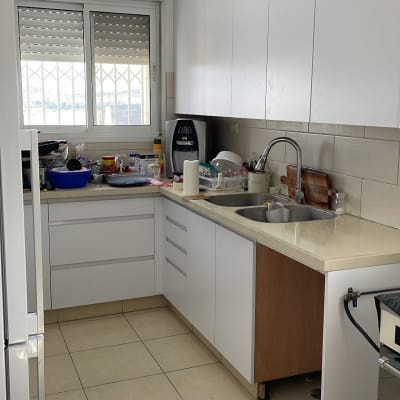 מטבח עם ארונות לבנים ומשטח עבודה מעץ