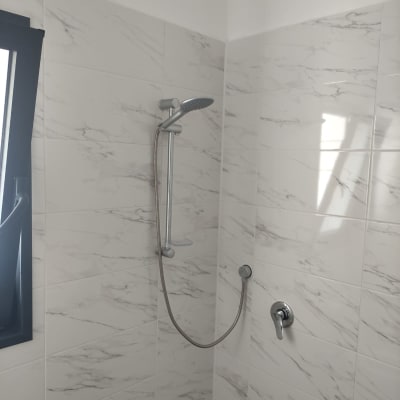 ראש מקלחת וכפתור מים על קיר אריחים