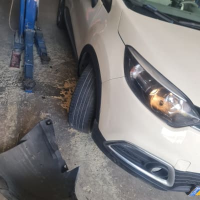 רכב במוסך עם חלק פלסטיק מנותק על הרצפה