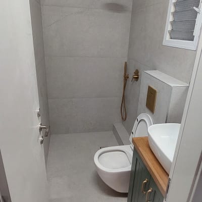 חדר אמבטיה משופץ עם מקלחת חדשה וברז זהב