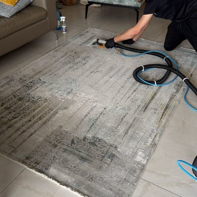 אדם מנקה שטיח עם מכונת ניקוי בסלון ביתי