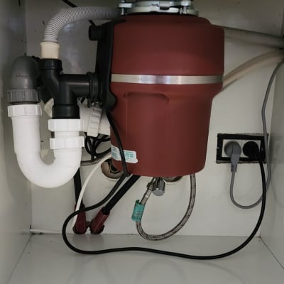 מתקן טוחן אשפה מתחת לכיור עם צינורות חיבור
