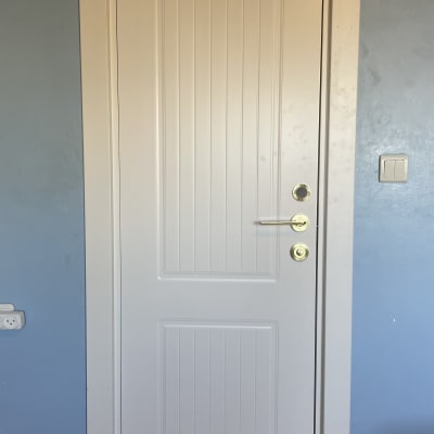 דלת לבנה עם ידית זהב וקישוטים אנכיים