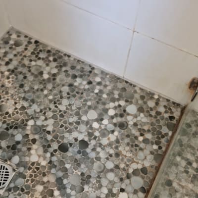 רצפת מקלחת עם אריחים עגולים ואיטום פינות